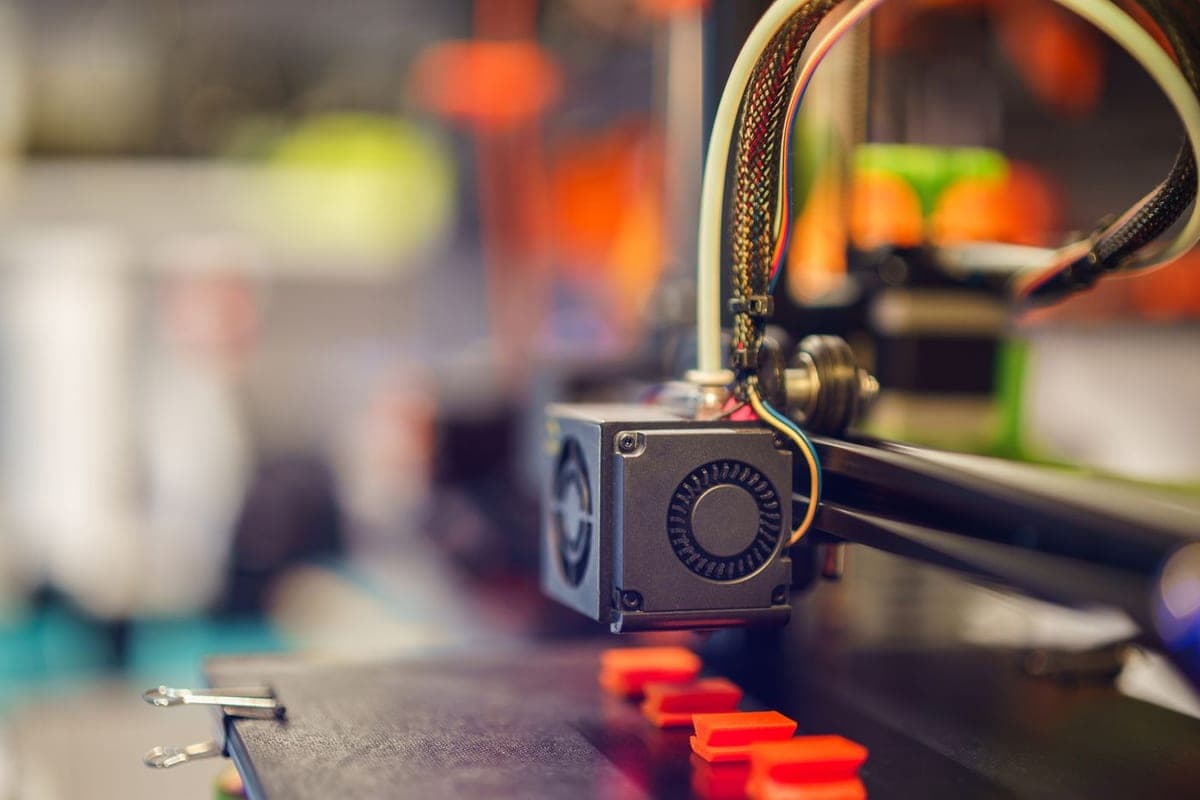 FDM 3D printer extruder head depositing filament onto the print bed